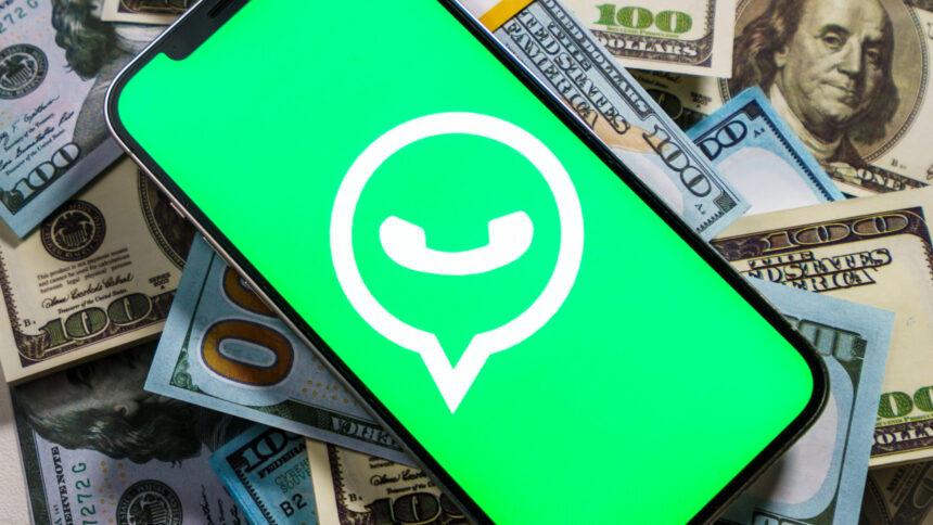 Smartphone mit Whatsapp-Logo auf dem Bildschirm liegt auf einem Stapel mit Dollarscheinen
