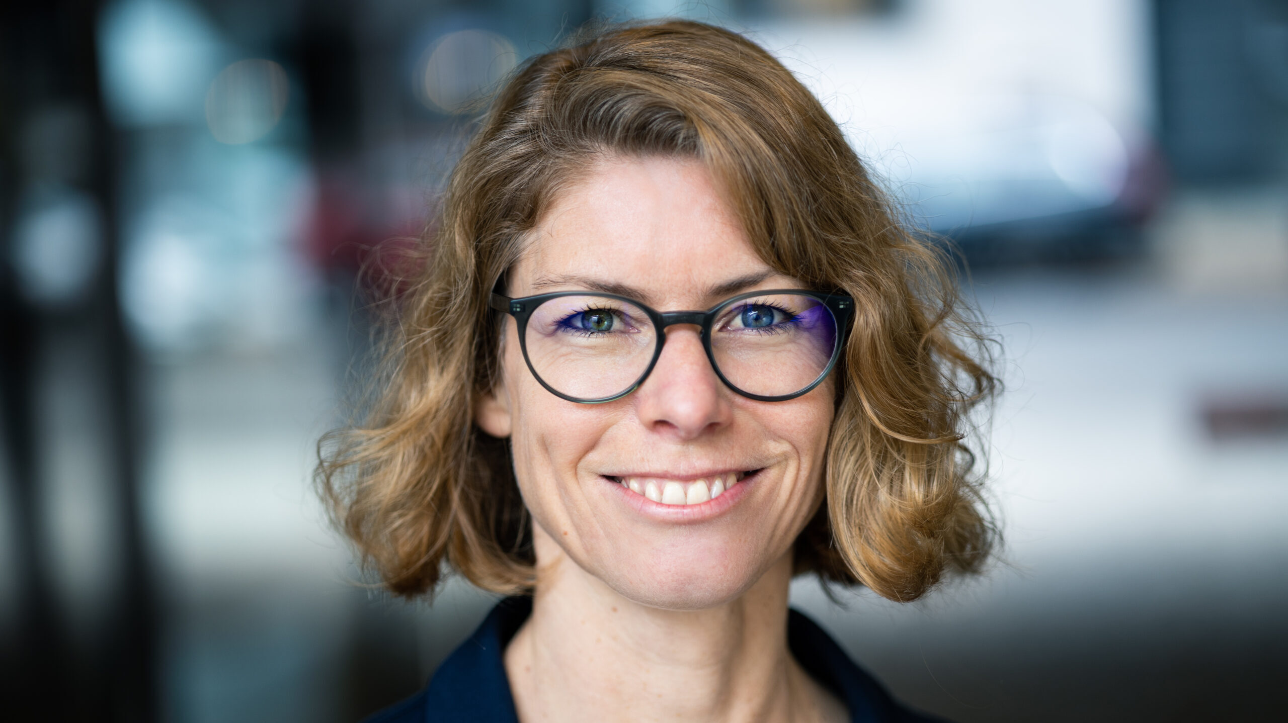 Eine Person mit Brille lächelt in die Kamera