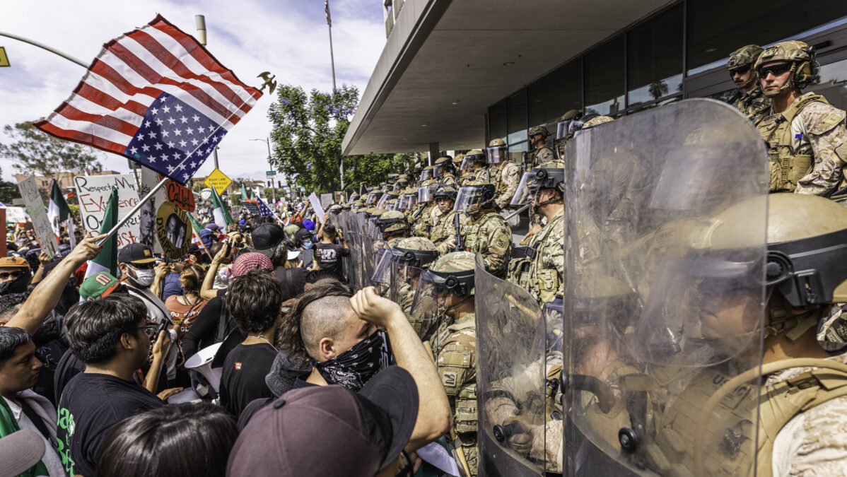 Protestierende stehen Sicherheitskräften mit Schildern und Helmen entgegen.