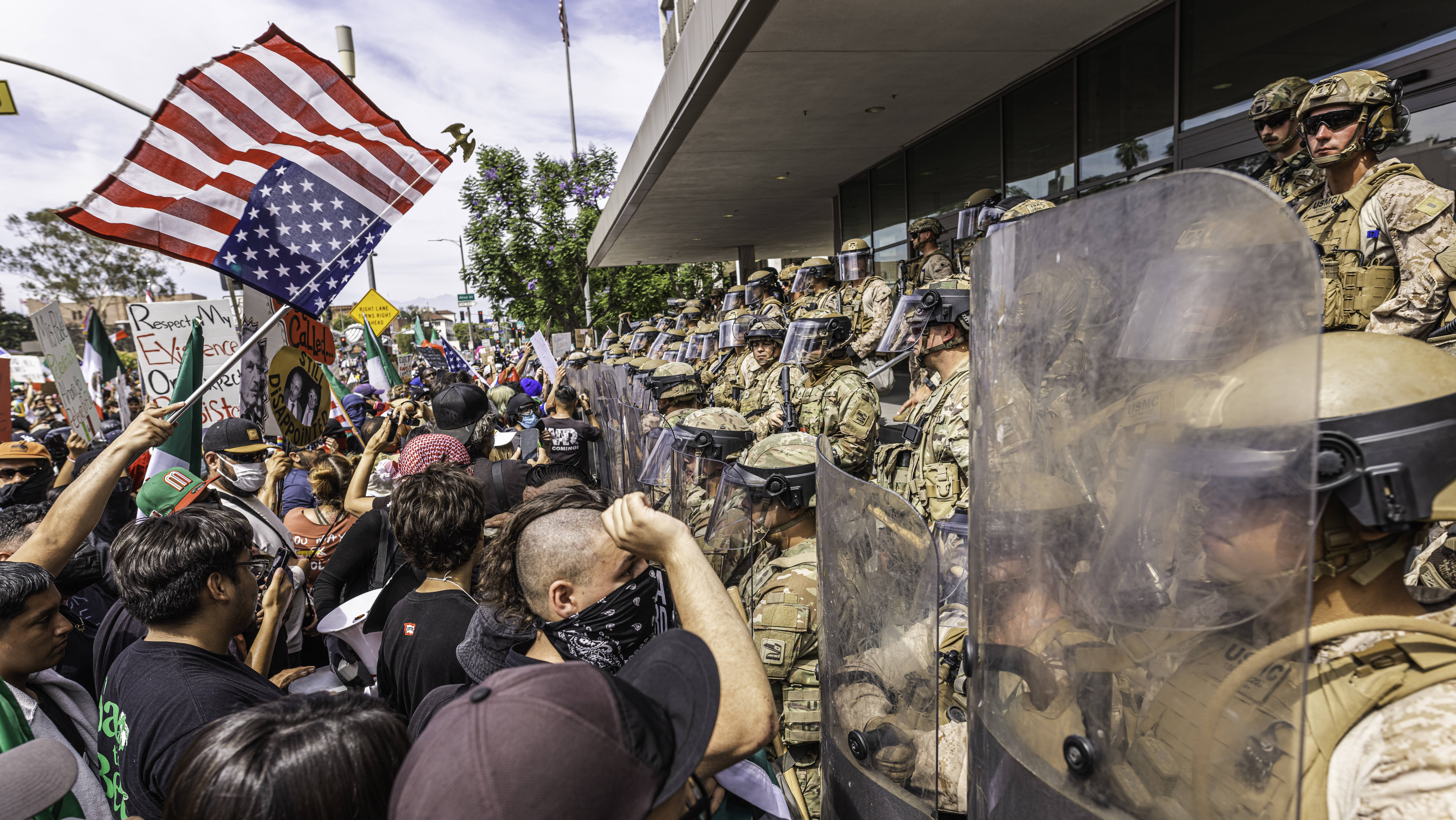 Protestierende stehen Sicherheitskräften mit Schildern und Helmen entgegen.