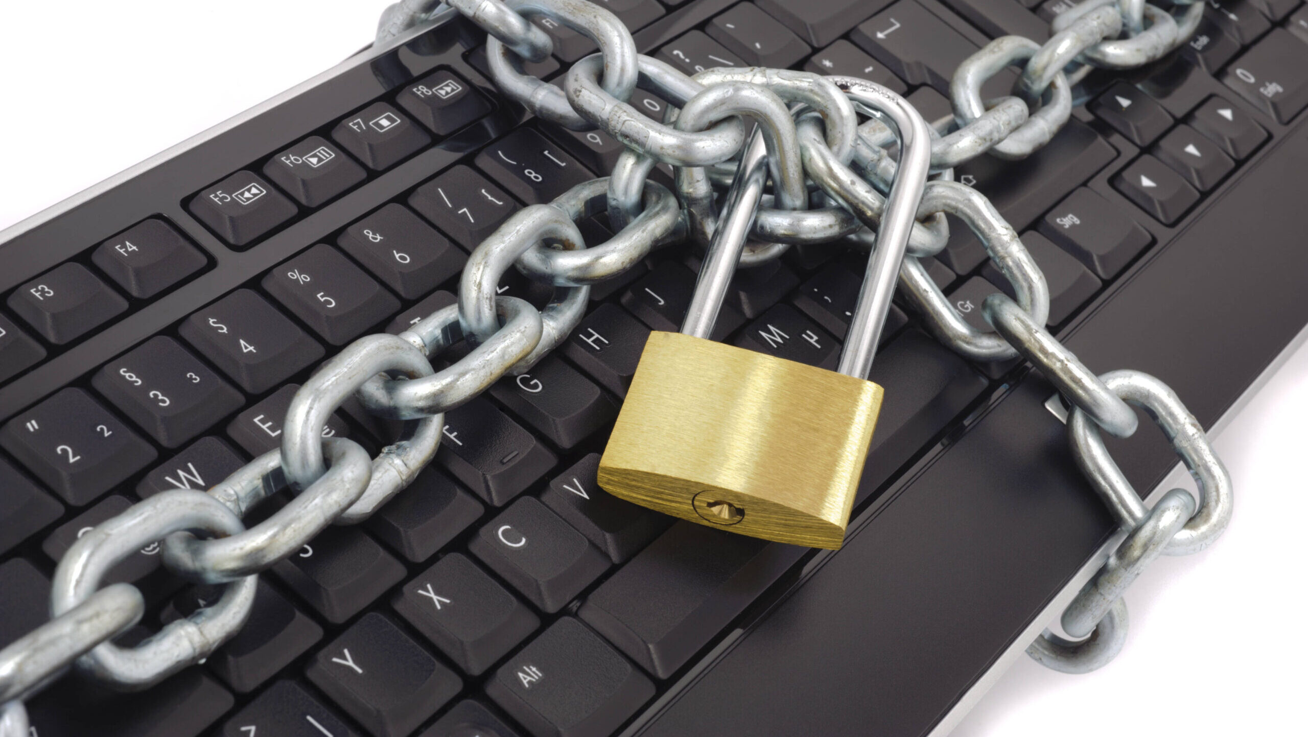 Eine Tastatur ist eine Kette eingewickelt, die von einem Vorhängeschloss zusammengehalten wird.