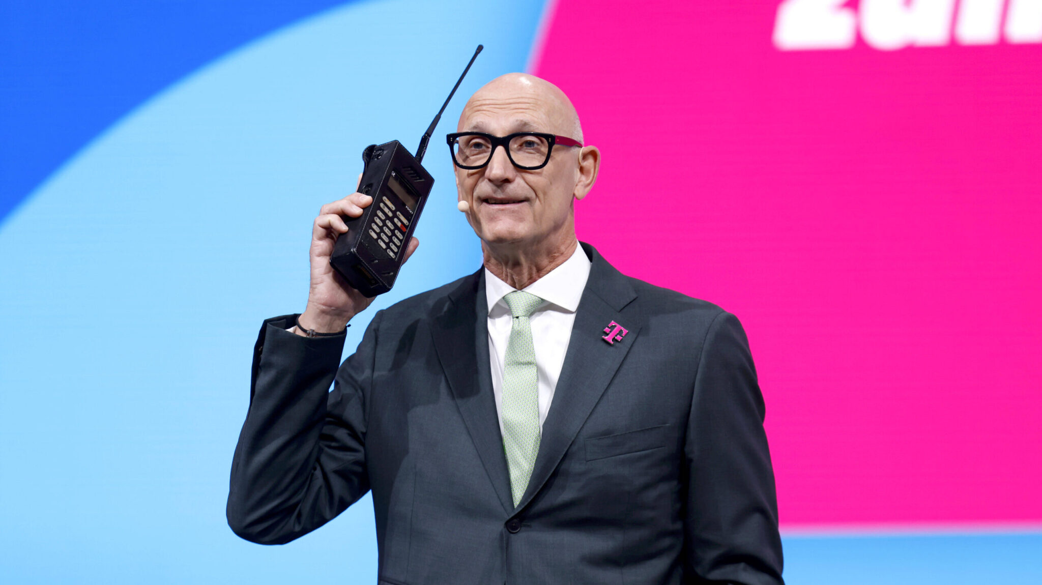 Telekom-Chef Timotheus Höttges, Vorstandsvorsitzender der Deutschen Telekom, mit einem historischen Mobiltelefon Pocky vor den Aktionären.