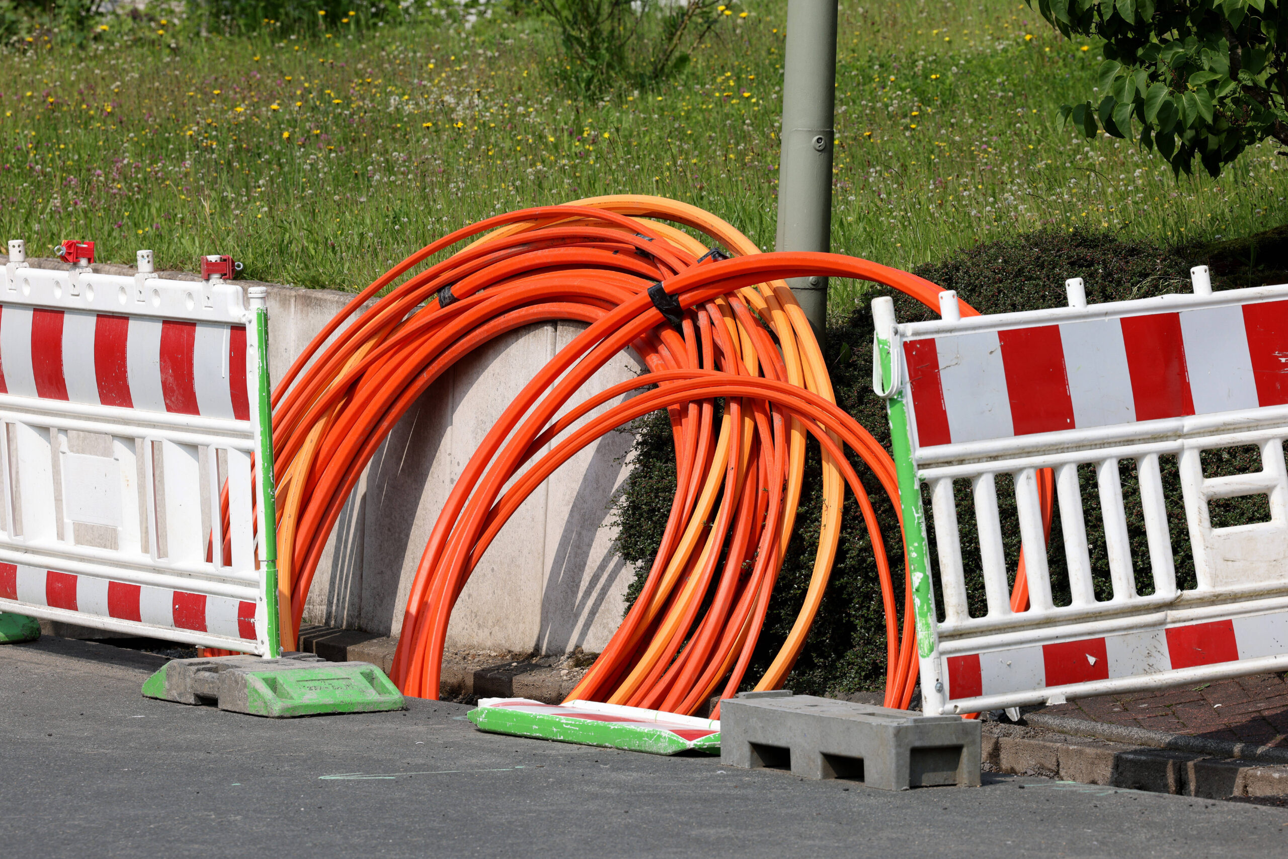 Glasfaserkabel in einem aufgebaggertem Loch mit Baustellenabsperrung.