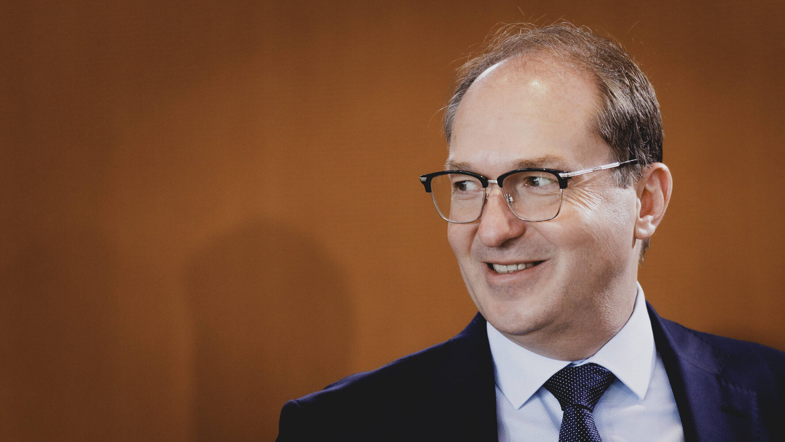 Mann mit Brille und Anzug lächelt dezent