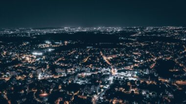 eine Stadt von oben bei Nacht, die Straßen ziehen sich wie Linien aus Licht durch die Stadt