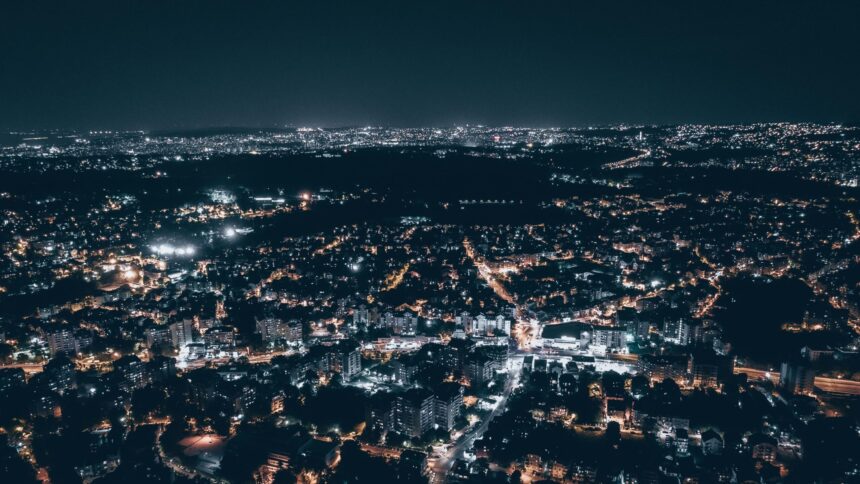 eine Stadt von oben bei Nacht, die Straßen ziehen sich wie Linien aus Licht durch die Stadt