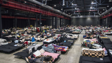 Eine Messehalle gefüllt mit temporären Betten für Geflüchtete