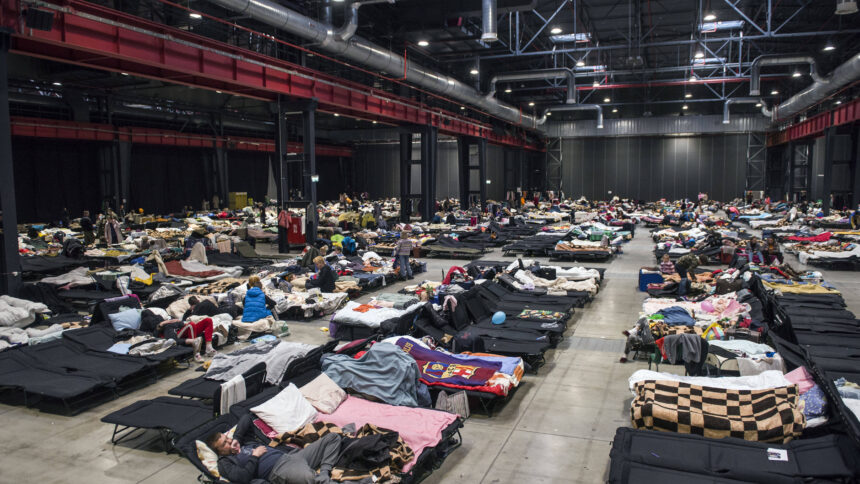 Eine Messehalle gefüllt mit temporären Betten für Geflüchtete