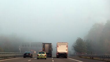 Blick auf eine Autobahn in Brandenburg, auf der ein paar Fahrzeuge in dichten Nebel fahren.