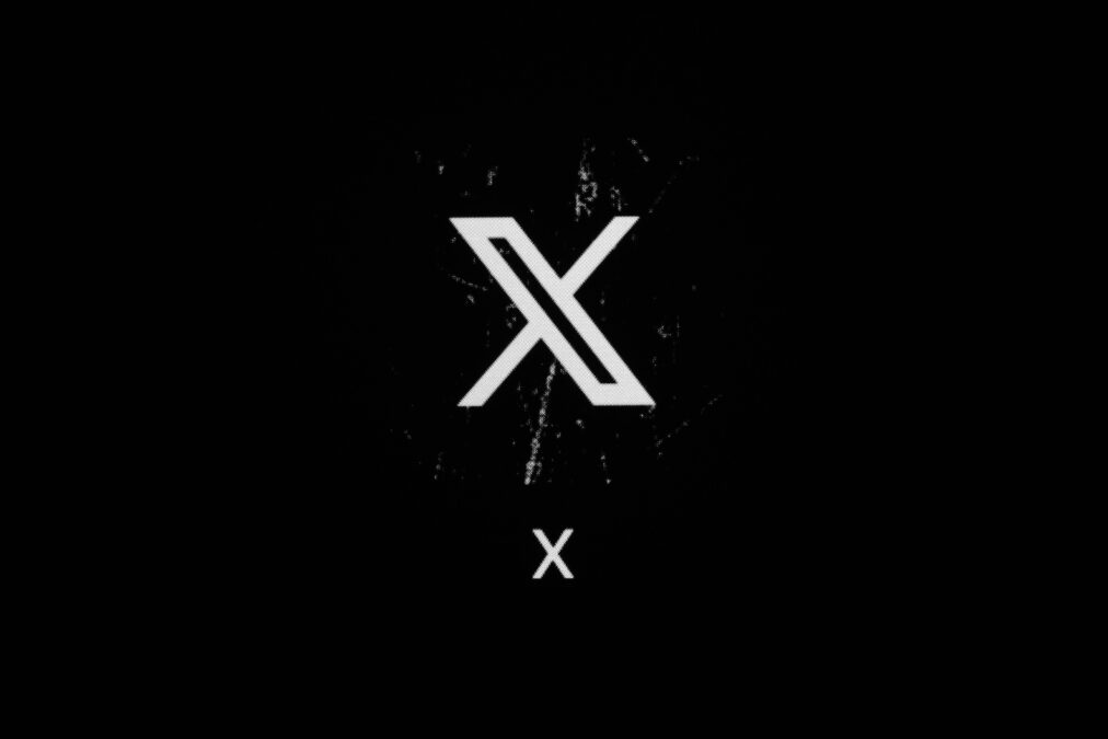 Das Logo der Plattform X - ein großes weiß-schwarzes X - vor schwarzem Hintergrund