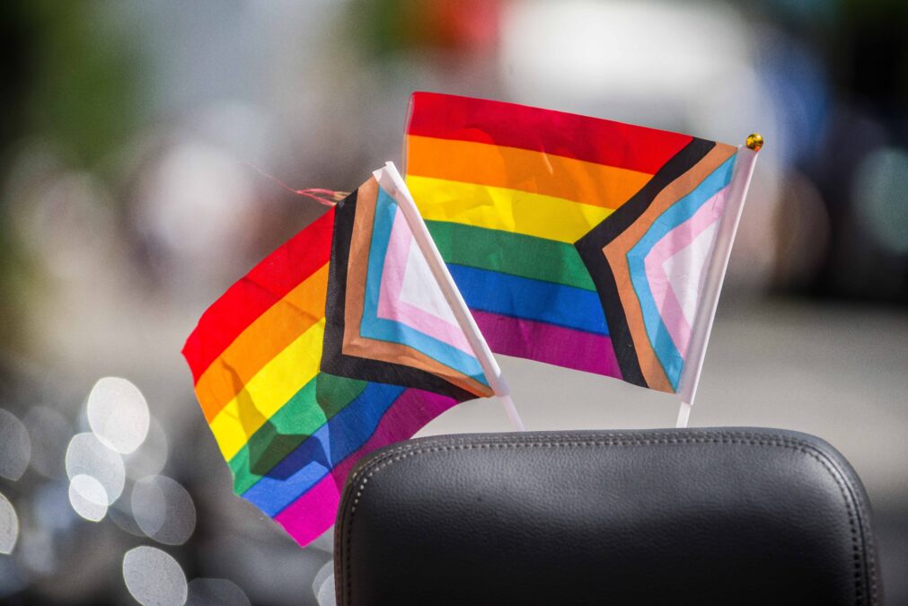 Zwei progressive pride flaggen stecken an einem schwarzen Stuhl