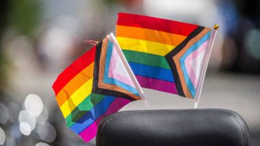 Zwei progressive pride flaggen stecken an einem schwarzen Stuhl
