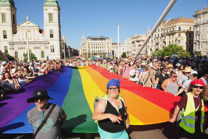 Menschen tragen ein Regenbogenbanner auf einer Demo