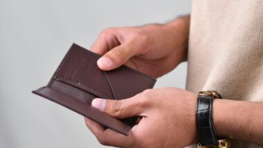 Die Hand einer Person hält eine lederne leere Geldbörse