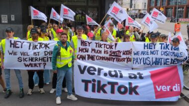 Eine Gruppe Menschen in ver.di-Warnwesten hält ein Banner.