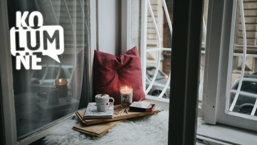 Eine gemütliche Sitzecke mit Duftkerze vor einem vergitterten Fenster