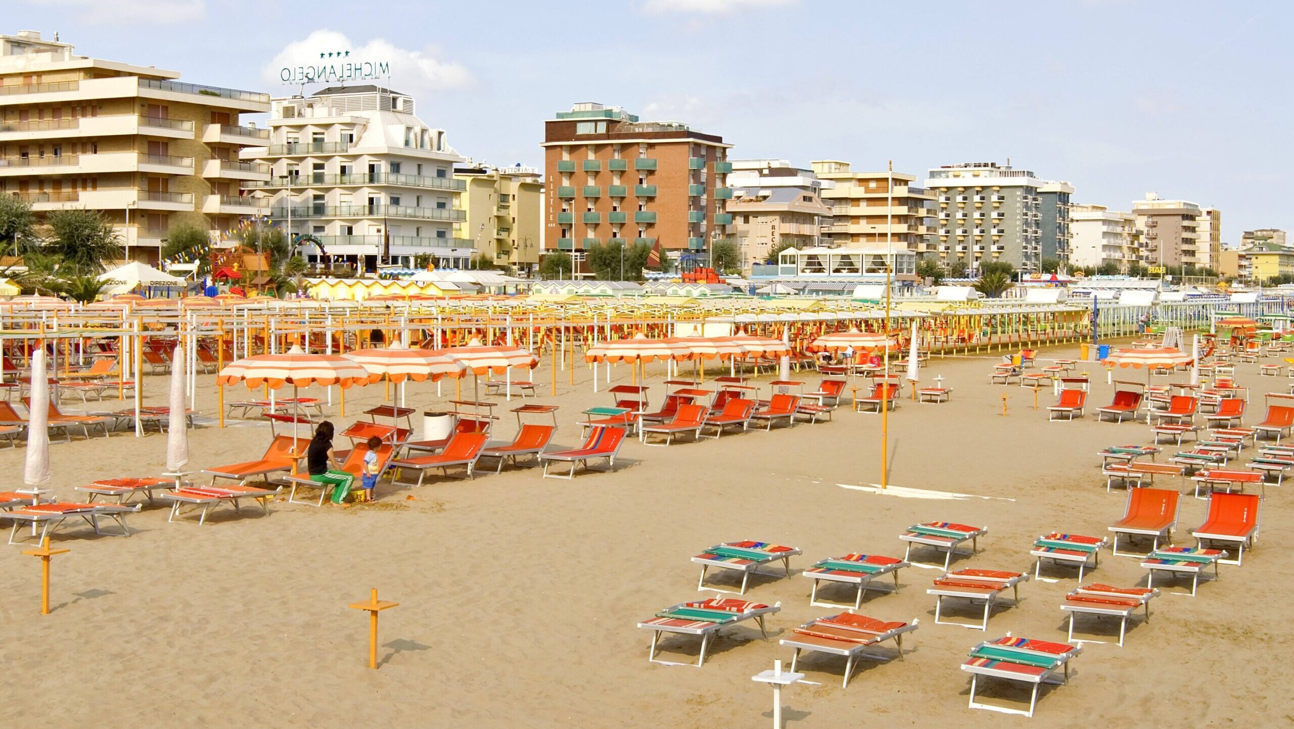 Strand mit Liegestühlen, im Hintergrund Hotels