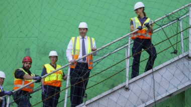 Vier Personen mit Helm und Warnweste auf einer Treppe