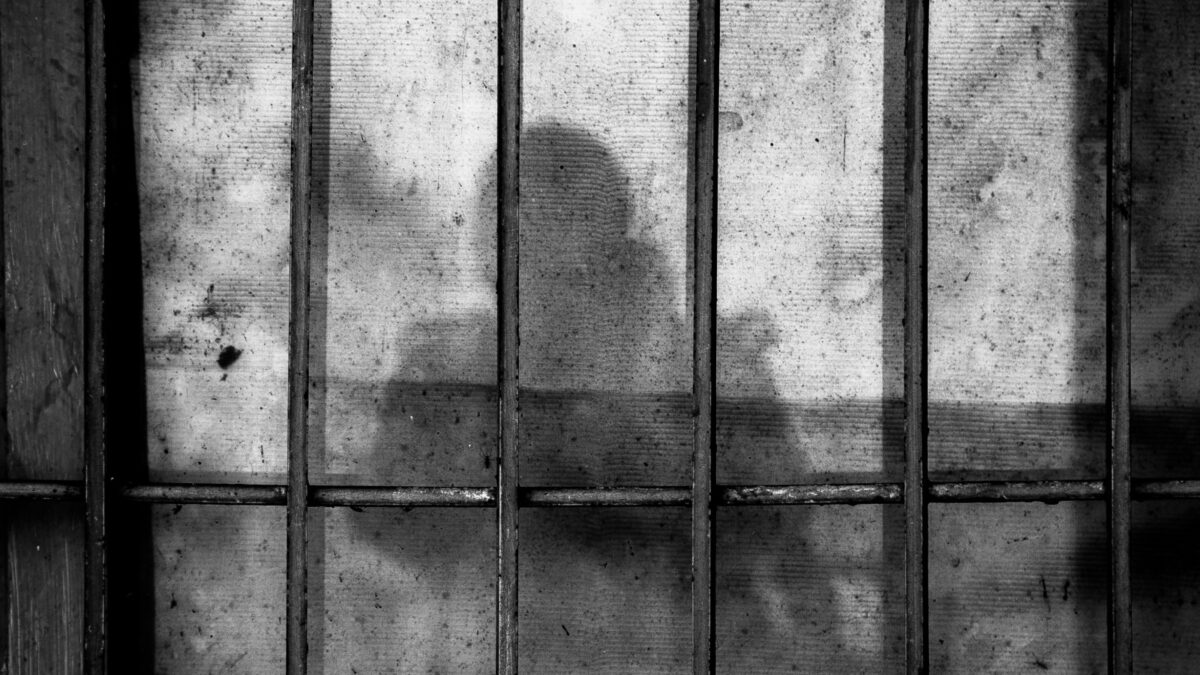 Ein menschlicher Schatten, der auf eine Wand hinter einem Gitter fällt