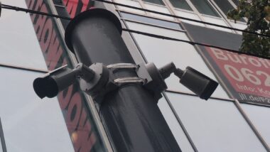 Zwei Kameras an einem Mast vor einer Fassade