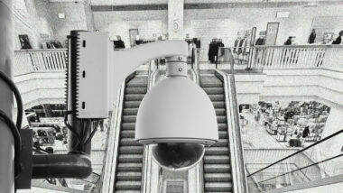 Überwachungskamera im Vordergrund, Foyer eines Einkaufszentrums im Hintergrund