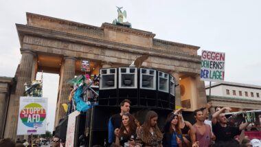 Menschen tanzen vor dem Brandenburger Tor während einer Demonstration gegen die AfD im Jahr 2018. Zu sehen sind große Lausprecherboxen.