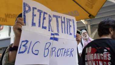 Mensch hält Plakat mit der Aufschrift "Peter Thiel = Big Brother"
