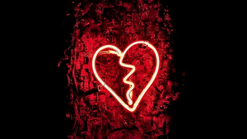 Ein gebrochenes Neonherz, das rot vor dunklem Hintergrund leuchtet.