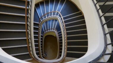 Ein altmodisch aussehendes Treppenhaus von oben. Es windet sich in Spiralen nach unten.