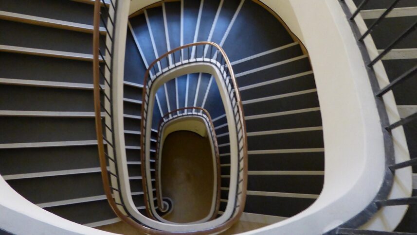 Ein altmodisch aussehendes Treppenhaus von oben. Es windet sich in Spiralen nach unten.