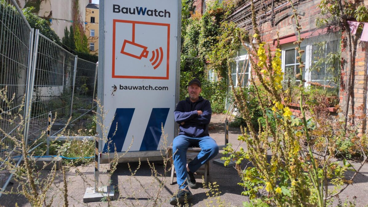 Ein Mann sitzt vor einem Kameraturm.