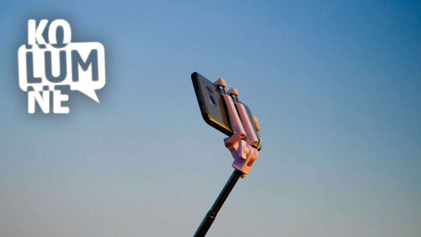 Ein Handy an einem Selfie-Stick vor blauem Himmel