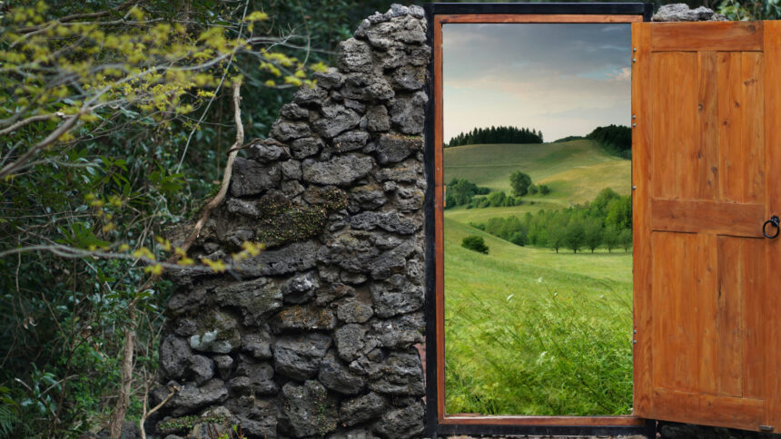 Eine offene Tür steht mitten in der Natur, durch die Öffnung sieht man eine Hügellandschaft.