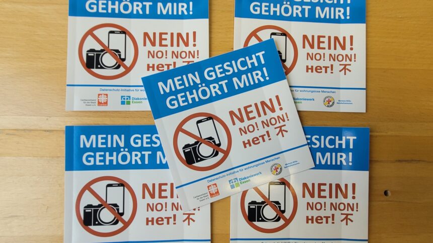 Sticker mit der Aufschrift "Mein Gesicht gehört mir!" liegen auf einem Holztisch.