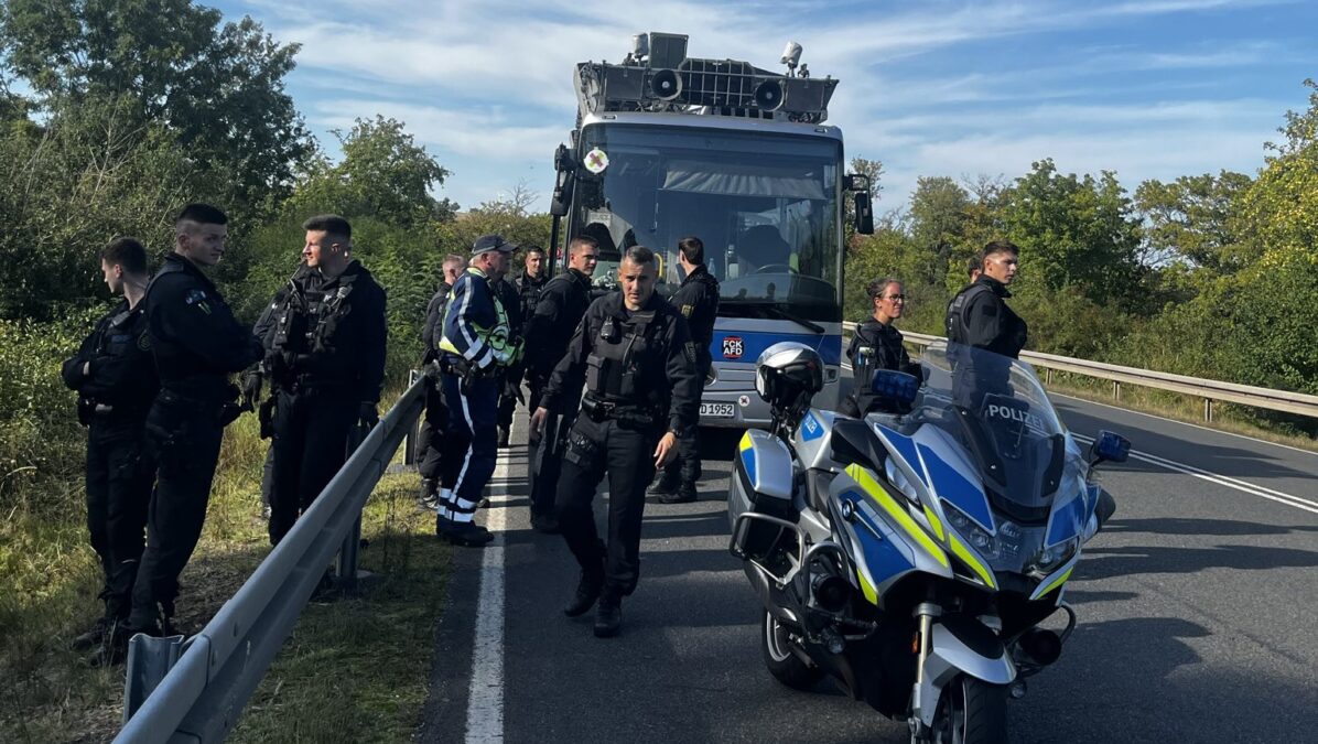 Polizeibeamte und ein Polizeimotorrad stehen vor einem Bus