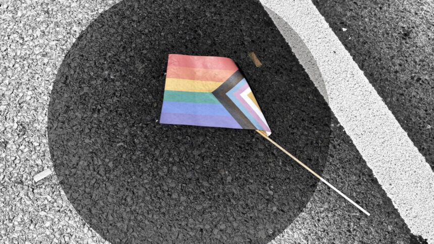 Progress-Pride-Papierflagge liegt zerknickt am Boden.