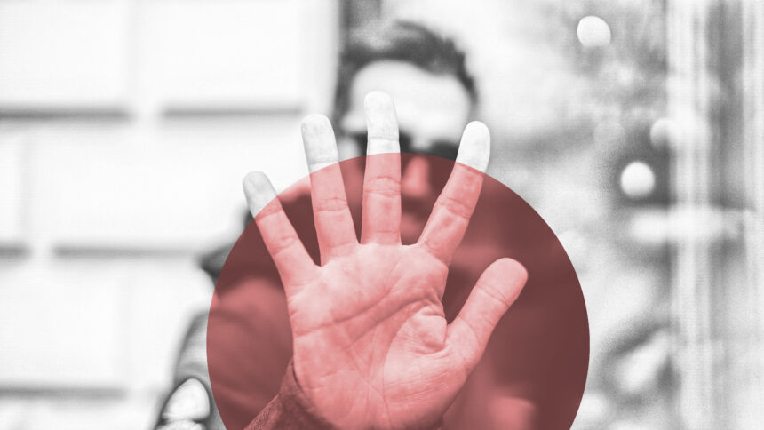 Person hält ablehnend die Hand vor sich, die Hand ist rot eingefärbt.