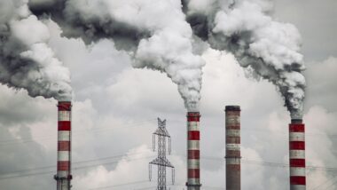 Schornsteine vor bewölktem Himmel aus denen Rauchwolken quillen