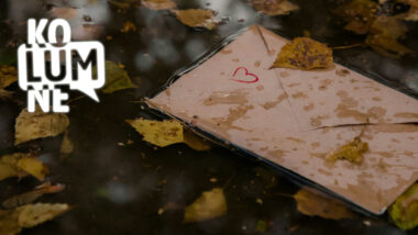 Briefumschlag mit aufgemaltem Herz liegt in einer Pfütze mit vielen Blättern