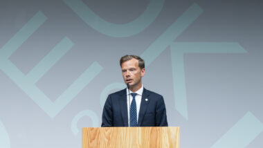 Mann im Anzug spricht in Mikrofon.