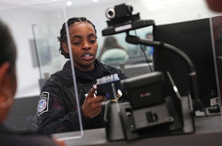 Eine Beamtin der US-Grenzschutzbehörde fertigt einen Reisenden am Washington International Thurgood Marshall Airport ab. Im Vordergrund ein Gerät mit Kamera.