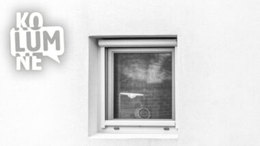 Fenster in einer weißen Wand, darin brennt ein Licht. Schwarz-weiß.