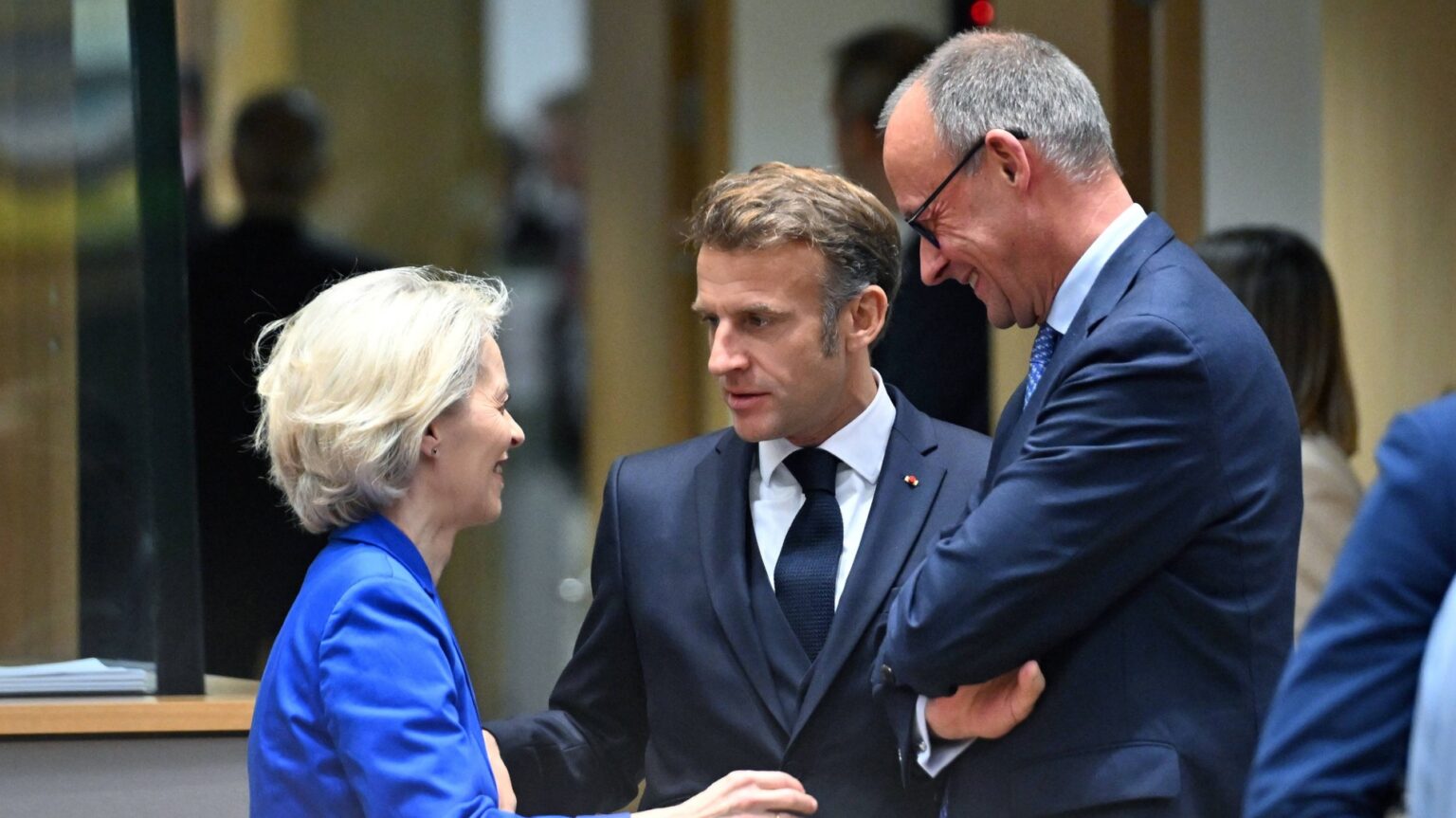 Drei Personen in formellen Setting sprechen und scherzen miteinander