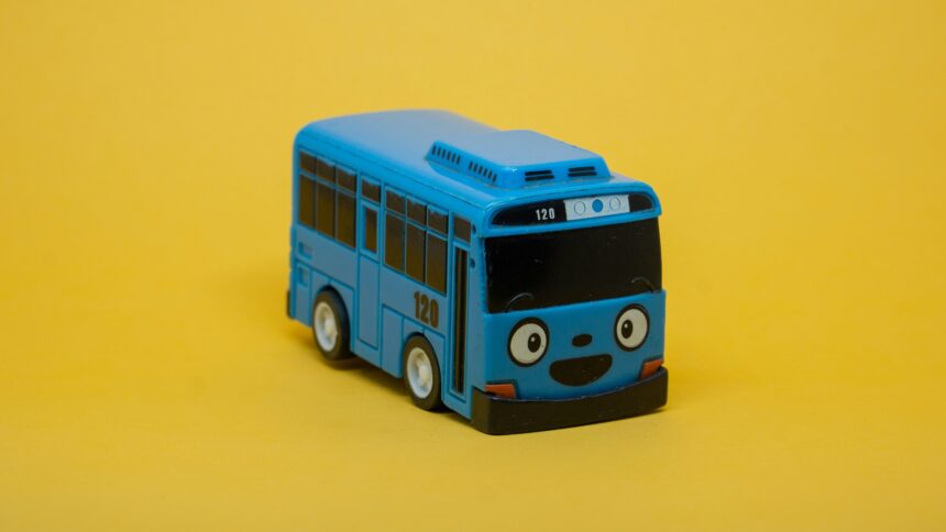 Ein kleiner blauer Spielzeug-Bus vor gelbem Hintergrund