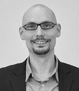 Schwarz-weißes Porträtfoto von einem jungen Mann mit Brille und Glatze