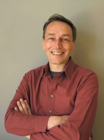 Mann lächelt mit gekreuzten Armen