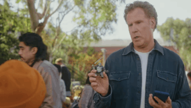 Schauspieler Will Ferrell steht auf einem Flohmakrt vor einem Jungen und hält eine Actionfigur in der Hand.