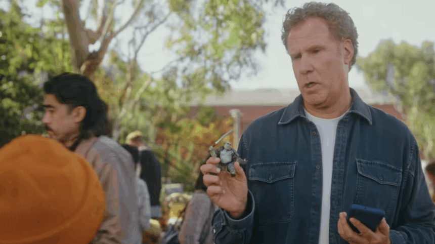 Schauspieler Will Ferrell steht auf einem Flohmakrt vor einem Jungen und hält eine Actionfigur in der Hand.