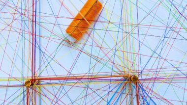 bunte Nähfäden, die über einer hellen Fläche kreuz und quer gespannt sind