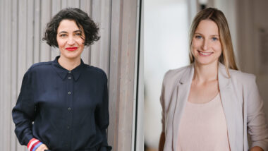 Das Bild zeigt zwei Porträts von Frauen, die nebeneinander platziert sind. Auf der linken Seite ist eine Frau mit dunklem, lockigem Haar und einem kräftigen roten Lippenstift zu sehen. Sie trägt eine dunkelblaue Bluse und steht vor einem Hintergrund aus Holzpaneelen. Rechts ist eine Frau mit langem, blondem Haar und einem strahlenden Lächeln zu sehen. Sie trägt ein helles Oberteil mit einem passenden Blazer. Der Hintergrund ist hell und unscharf. Beide Frauen schauen direkt in die Kamera und vermitteln einen freundlichen und professionellen Eindruck.